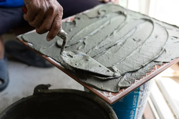 Person verteilt Fliesenkleber mit Kelle